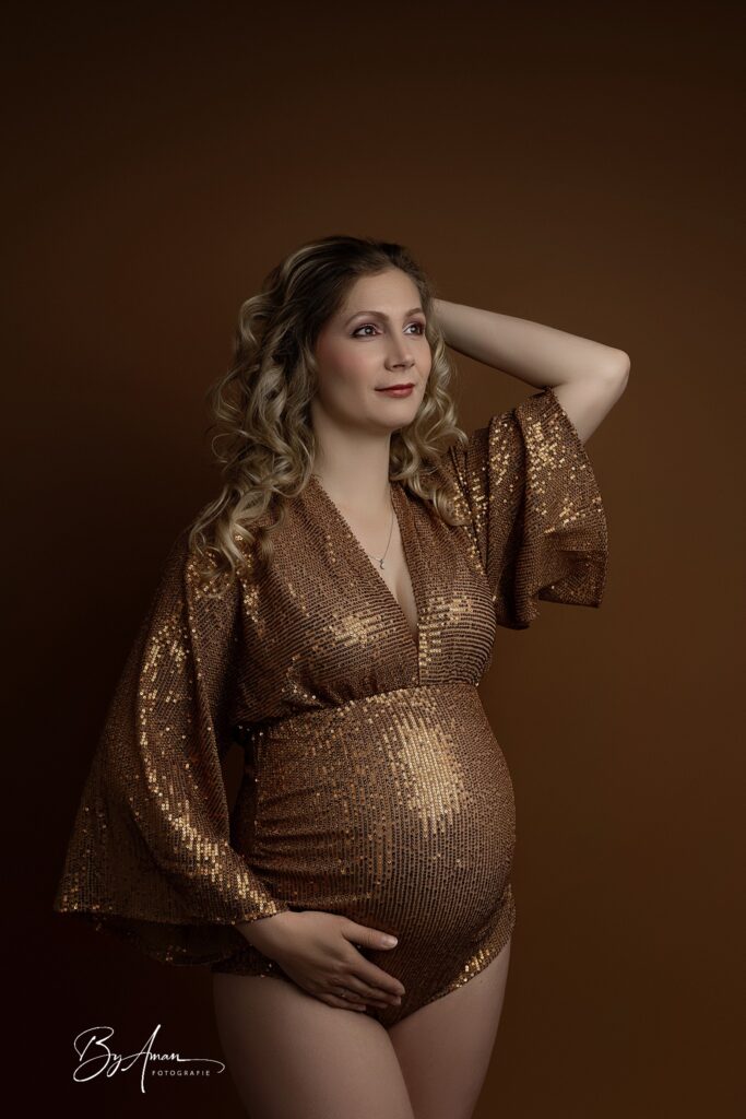 zwangere in de studio met een bronzen body met pailletten